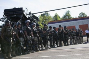 Riot police stand guard while demonstrators protest the shooting death of teenager Michael Brown, in Ferguson, Missouri